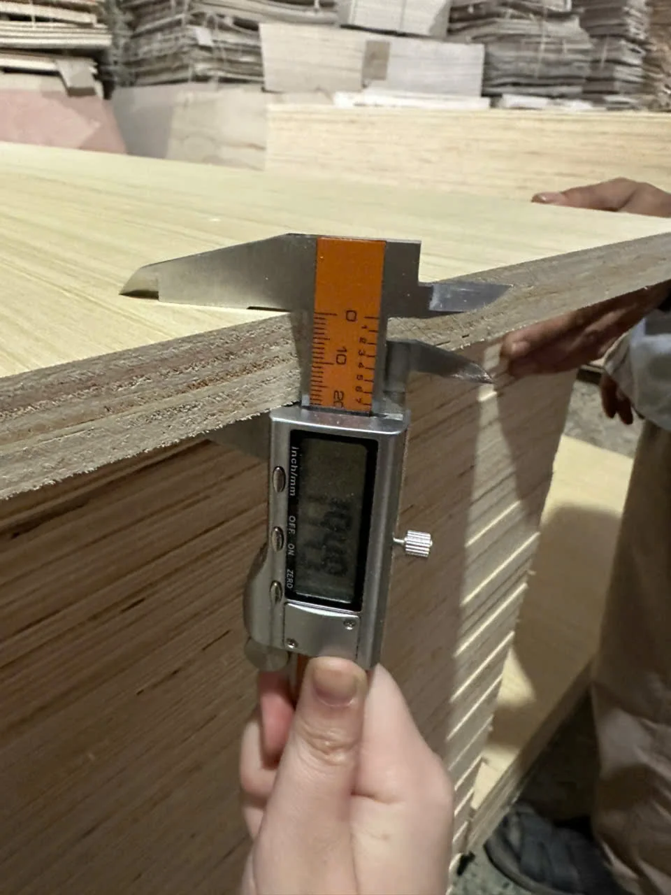 Plywood thickness measurement with digital caliper showing weight calculation at HCPLY factory Vietnam